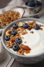 Photo of Bowl with yogurt, blueberries and granola on grey table, closeup