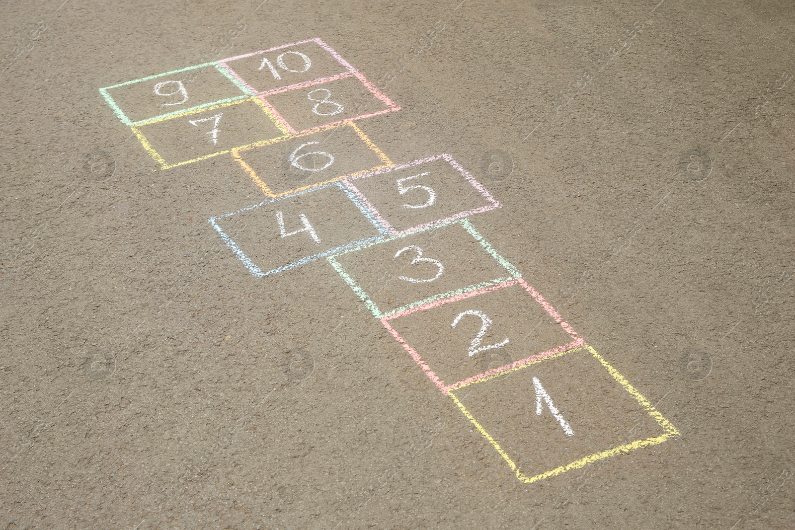 Photo of Hopscotch drawn with colorful chalk on asphalt outdoors