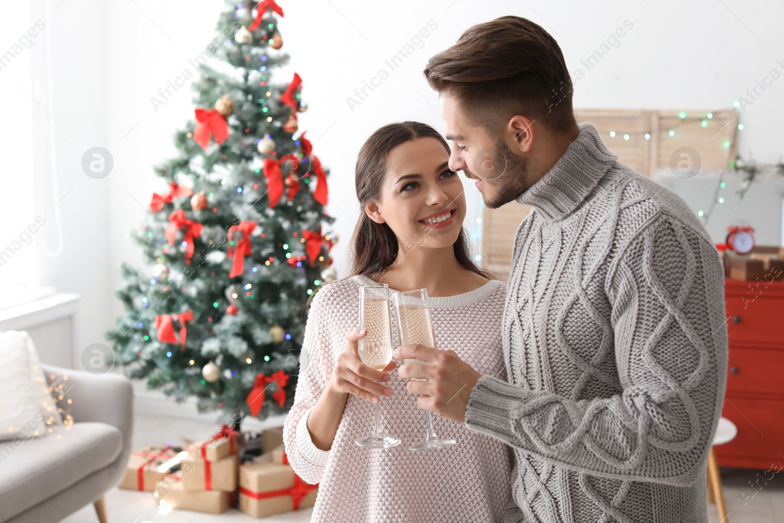 Photo of Happy young couple with glasses of champagne celebrating Christmas at home