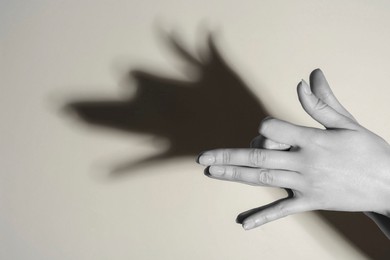 Photo of Shadow puppet. Woman making hand gesture like dog on light background, closeup. Black and white effect