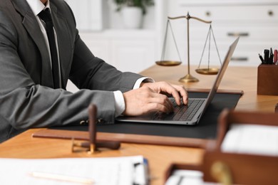 Photo of Notary working with laptop at wooden table in office, closeup