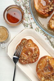 Photo of Delicious quinces baked with honey and walnuts on white wooden table, flat lay