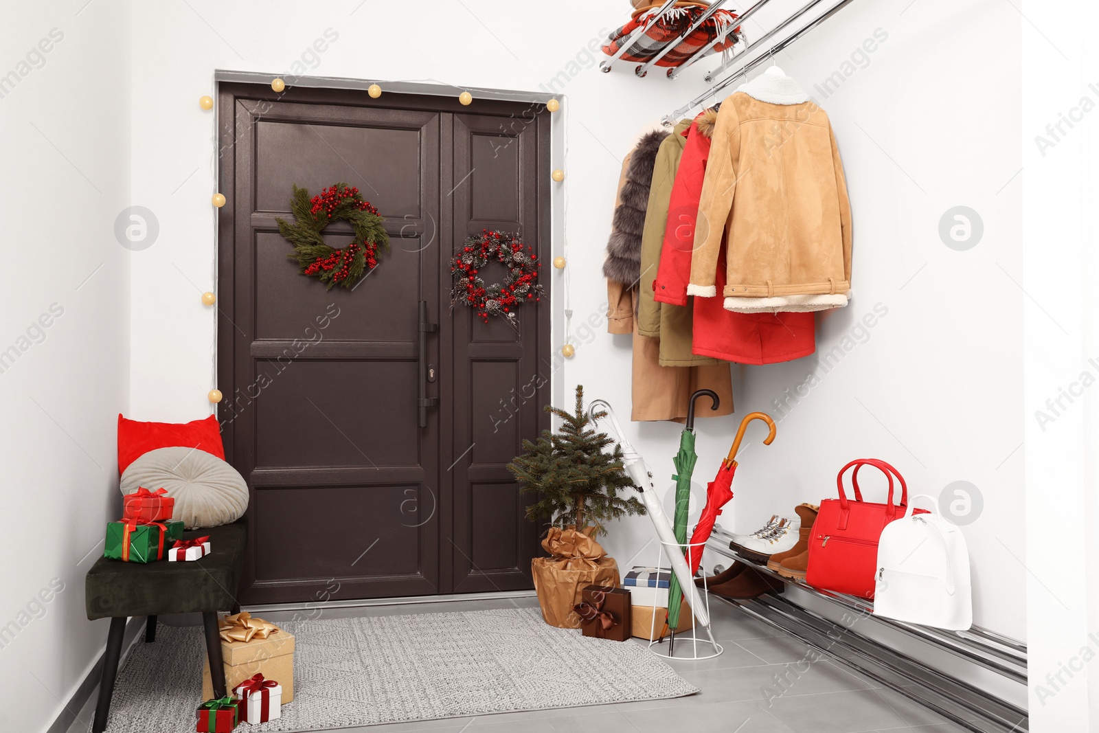 Photo of Christmas wreaths hanging on wooden door, festive decoration and outwear indoors