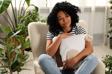 Photo of Woman relaxing in armchair near beautiful houseplants at home