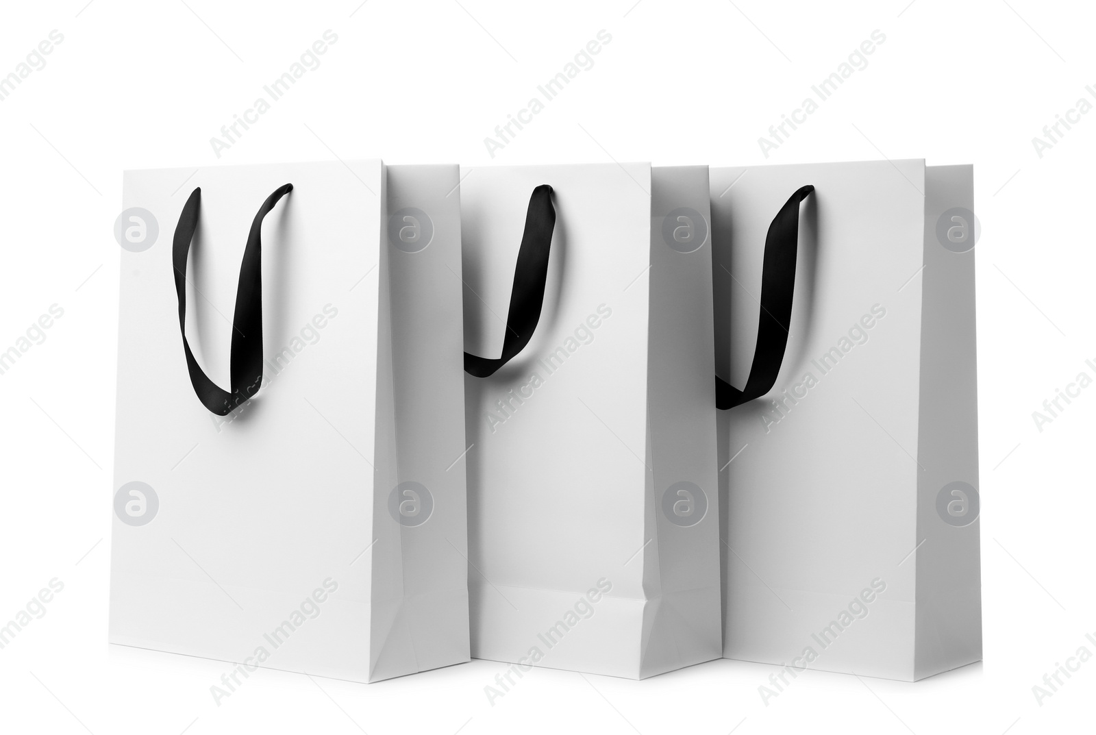 Photo of Paper shopping bags with ribbon handles on white background. Mockup for design