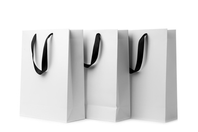 Paper shopping bags with ribbon handles on white background. Mockup for design