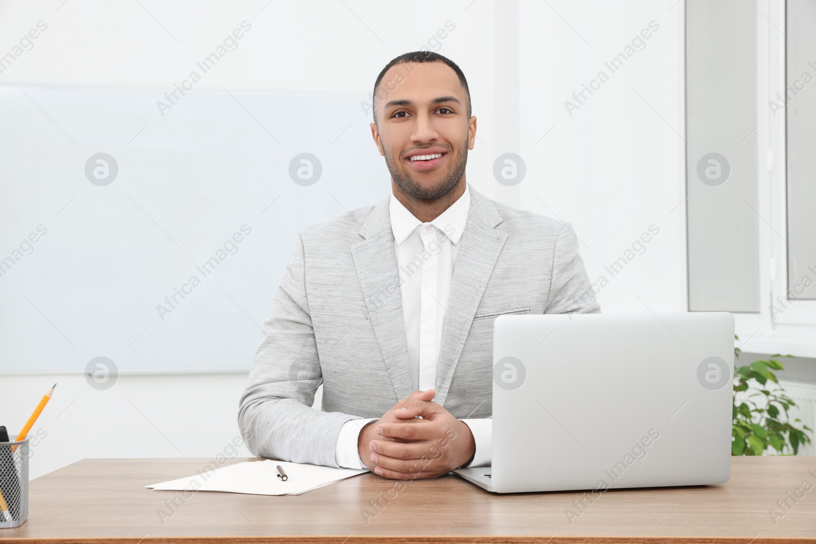 Photo of Happy young intern working at table in modern office