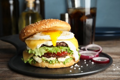 Photo of Tasty burger with fried egg on tray against blurred background