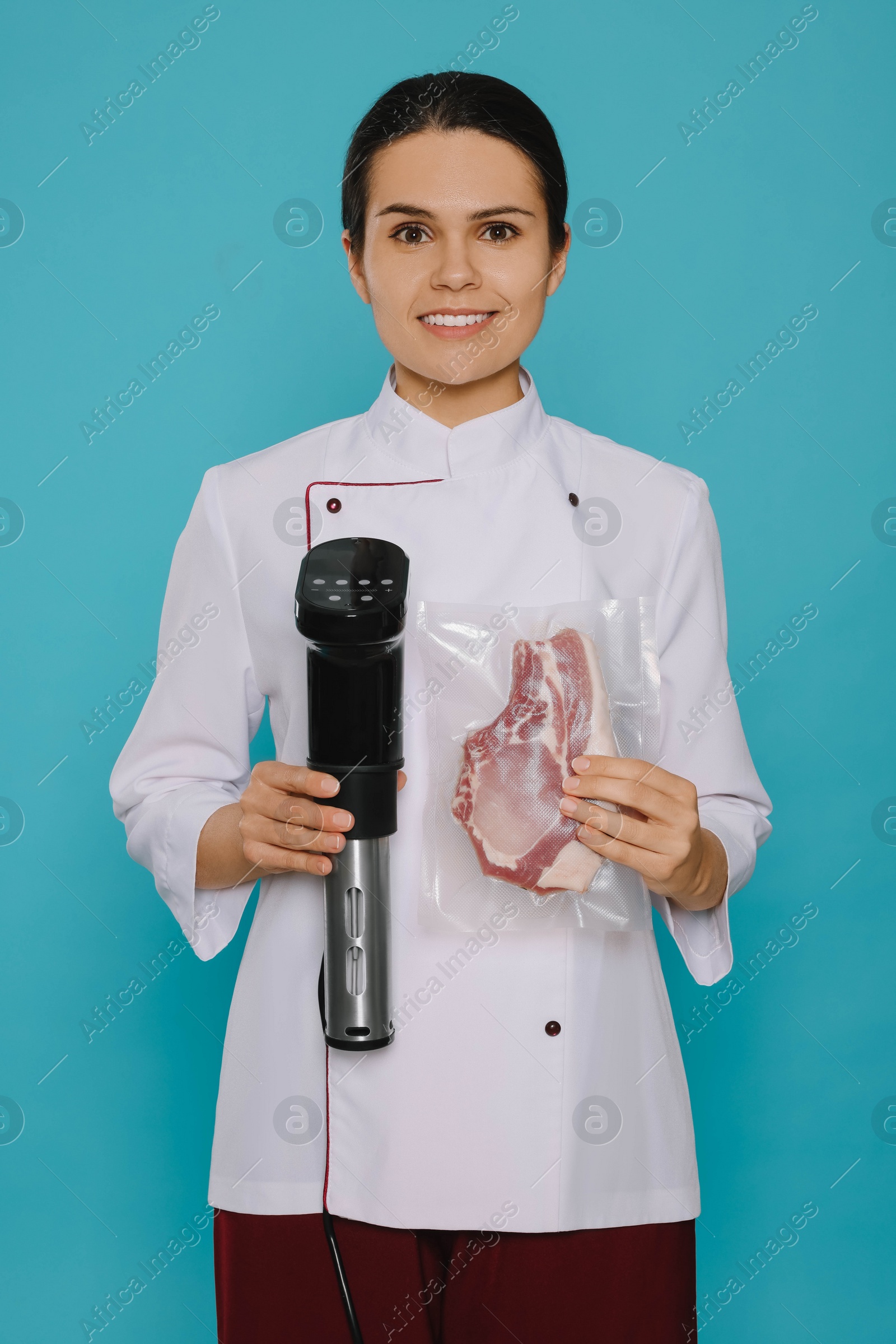 Photo of Chef holding sous vide cooker and meat in vacuum pack on light blue background