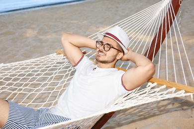 Photo of Young man resting in hammock at seaside. Summer vacation