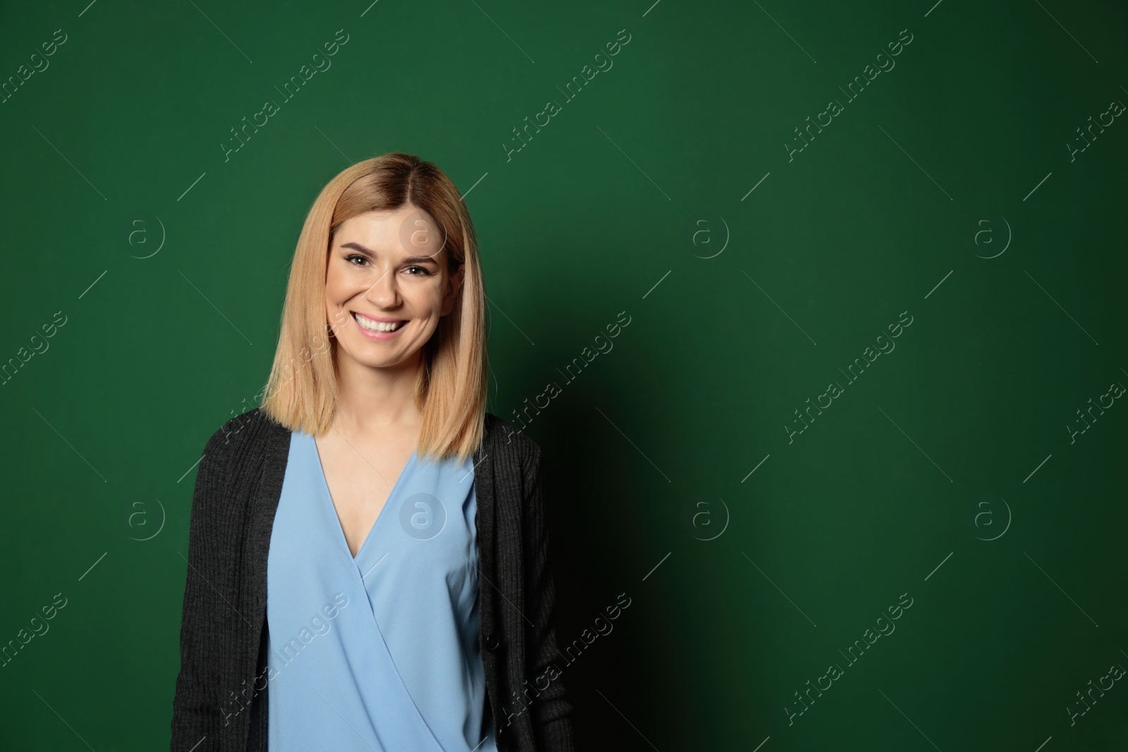 Photo of Portrait of beautiful teacher near chalkboard, space for text