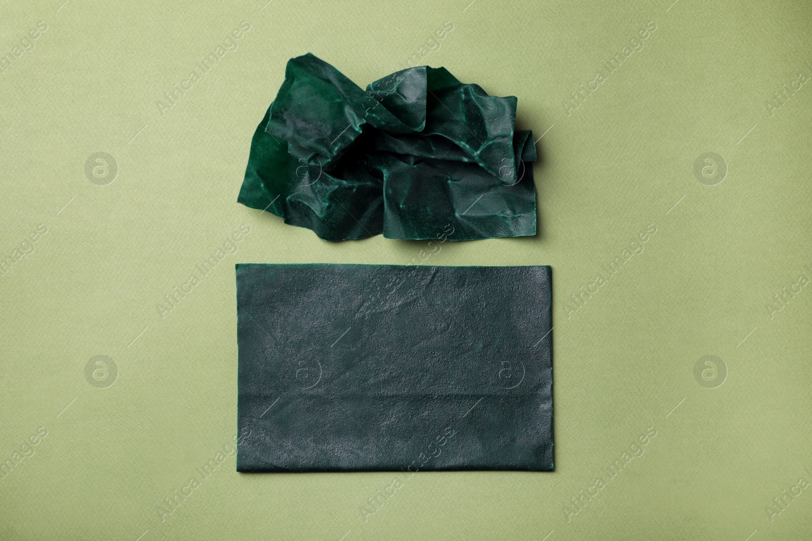 Photo of Reusable beeswax food wraps on green background, flat lay