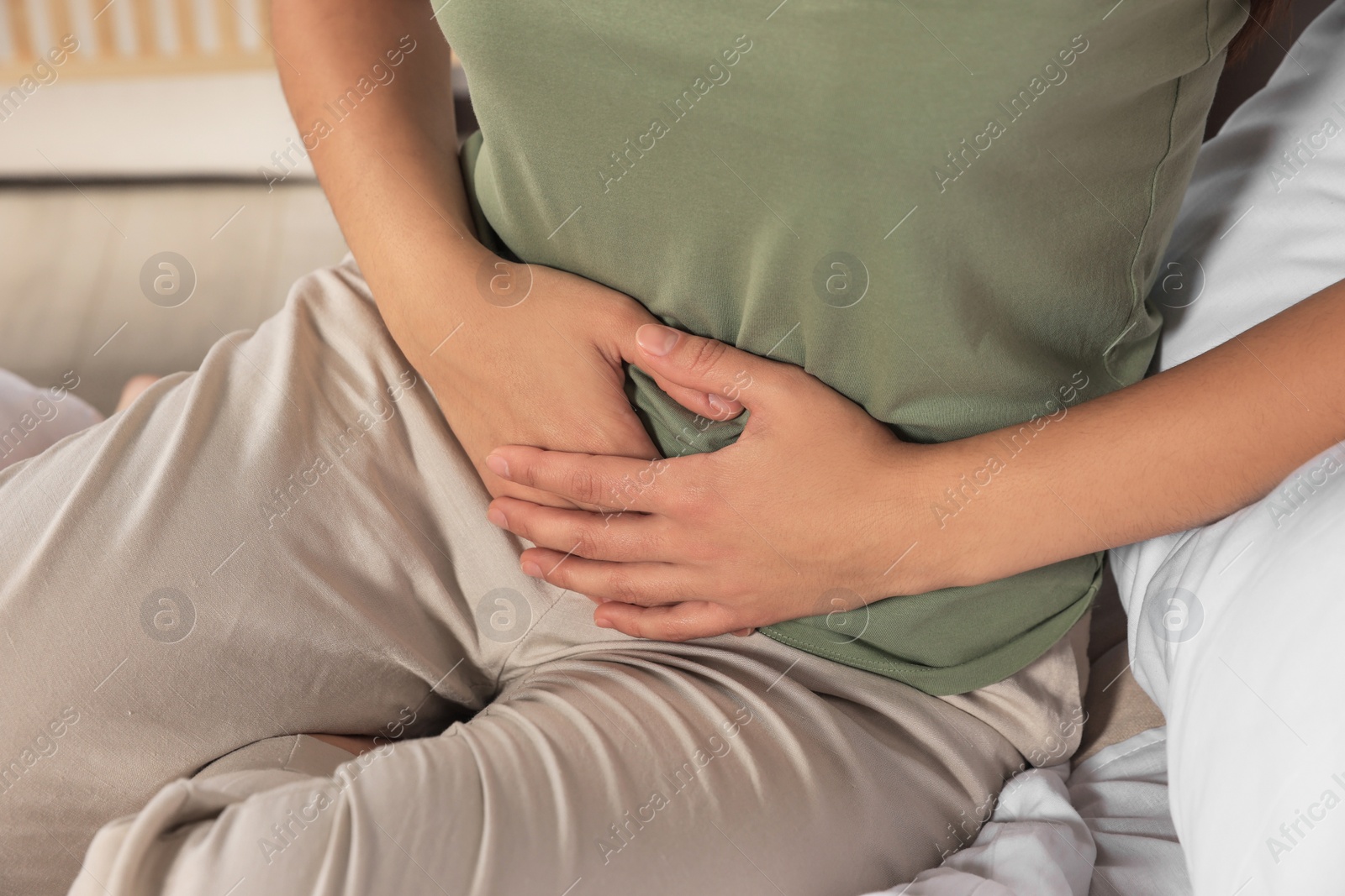 Photo of Young woman suffering from cystitis on bed indoors, closeup