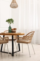 Photo of Dining room interior with comfortable furniture and green branches