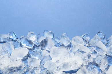 Photo of Pieces of crushed ice on light blue background, flat lay. Space for text