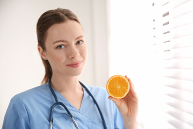 Photo of Nutritionist with orange near window in office