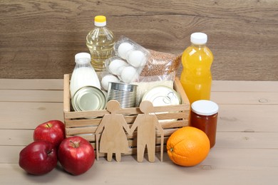 Humanitarian aid for elderly people. Different donation food and figures of senior couple on wooden table