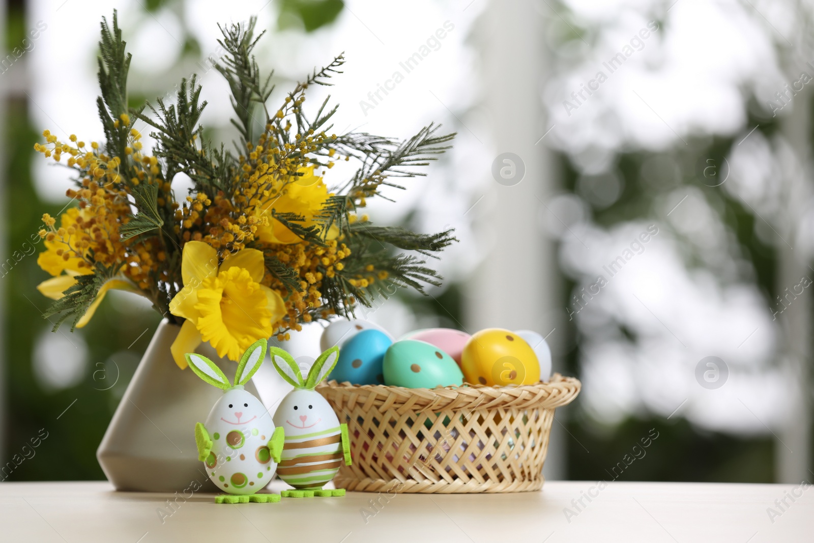 Photo of Festive composition with Easter eggs on table against blurred window, space for text