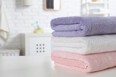 Photo of Stack of fresh towels on table in bathroom, closeup. Space for text