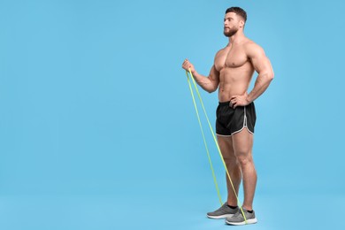 Photo of Young man exercising with elastic resistance band on light blue background. Space for text