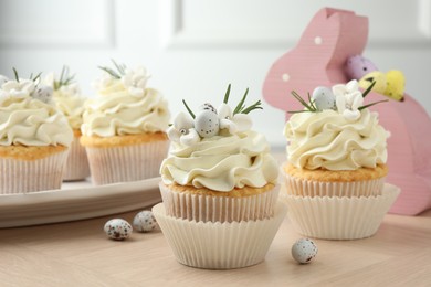 Photo of Tasty Easter cupcakes with vanilla cream on wooden table