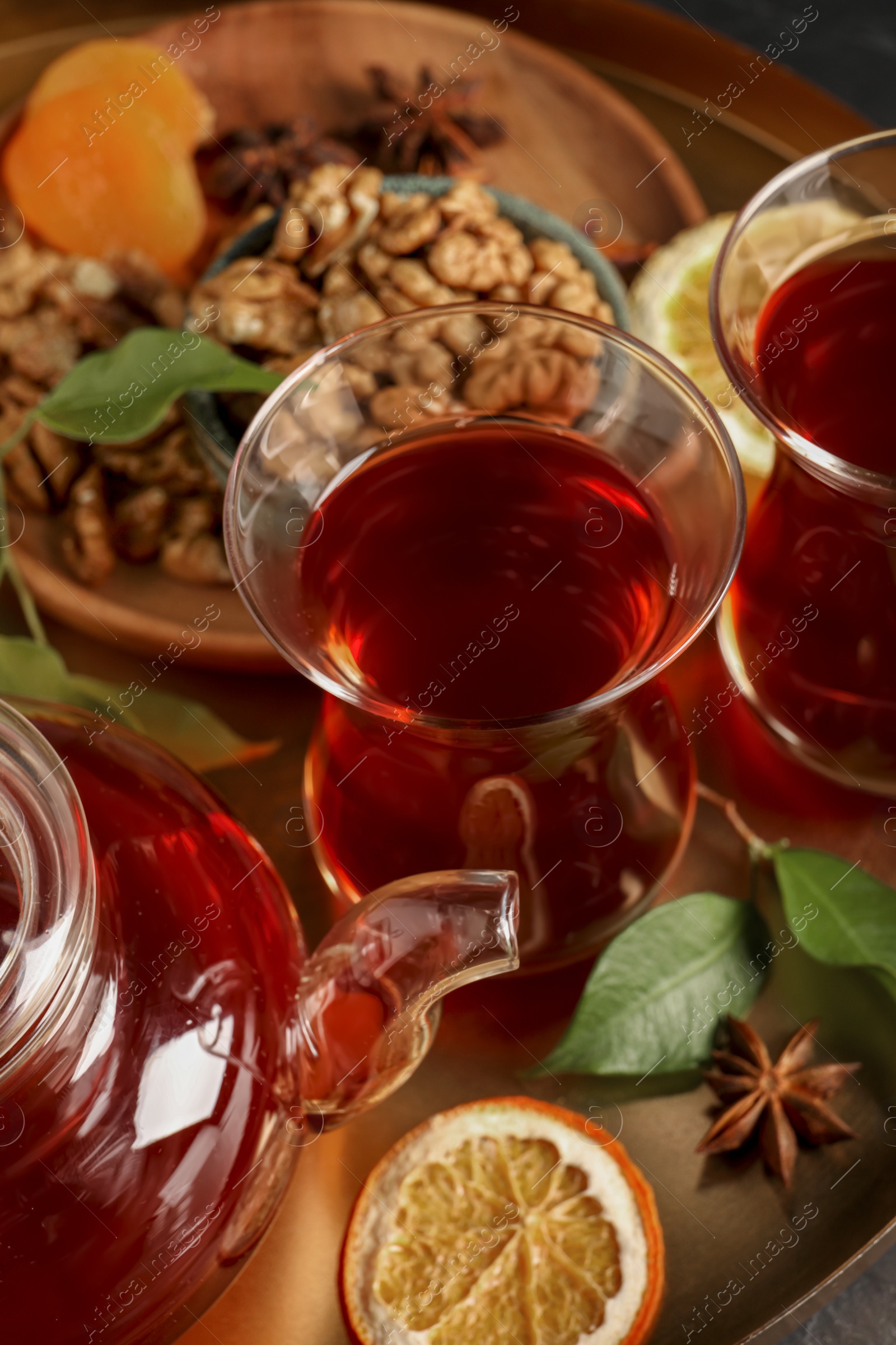 Photo of Tray with glasses of traditional Turkish tea, pot and ingredients, closeup