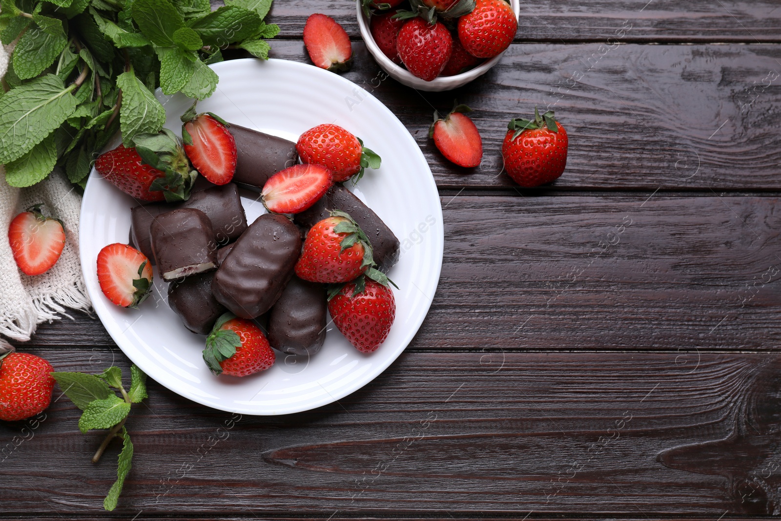 Photo of Delicious glazed curd snacks, mint leaves and fresh strawberries on wooden table, flat lay. Space for text