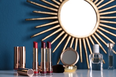 Bright lipsticks in gold tubes on dressing table, space for text