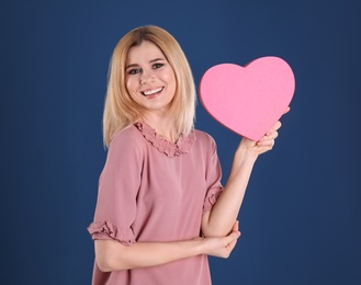 Photo of Beautiful woman with heart shaped box on color background
