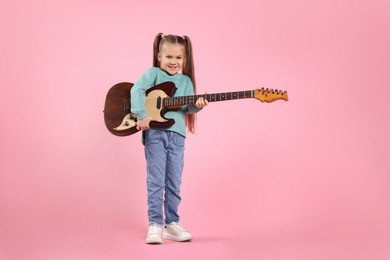 Happy girl with electric guitar on pink background. Space for text