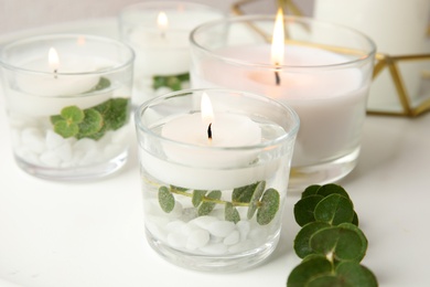 Composition with burning aromatic candles and eucalyptus on table