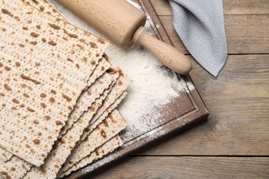 Photo of Stack of matzos and rolling pin on wooden table, flat lay
