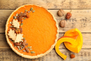 Photo of Delicious homemade pumpkin pie on wooden table, flat lay