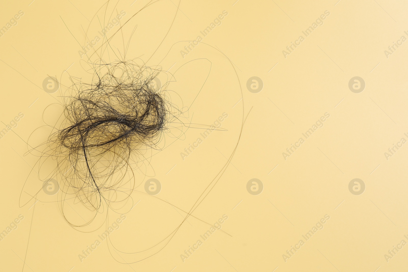 Photo of Pile of lost hair on yellow background, top view. Space for text