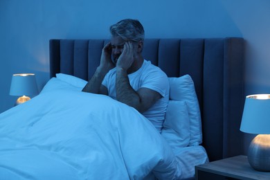 Mature man suffering from headache in bed at night