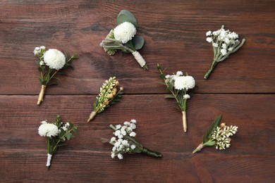 Photo of Small stylish boutonnieres on wooden table, flat lay
