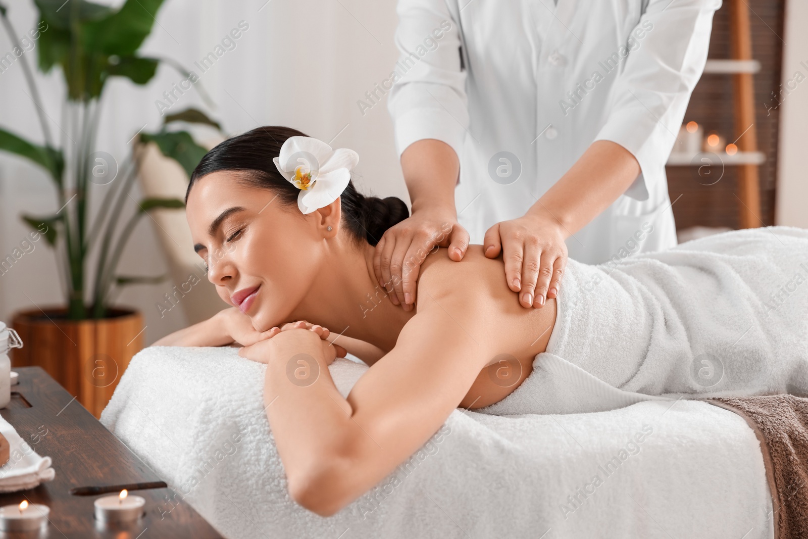 Photo of Young woman enjoying professional massage in spa salon