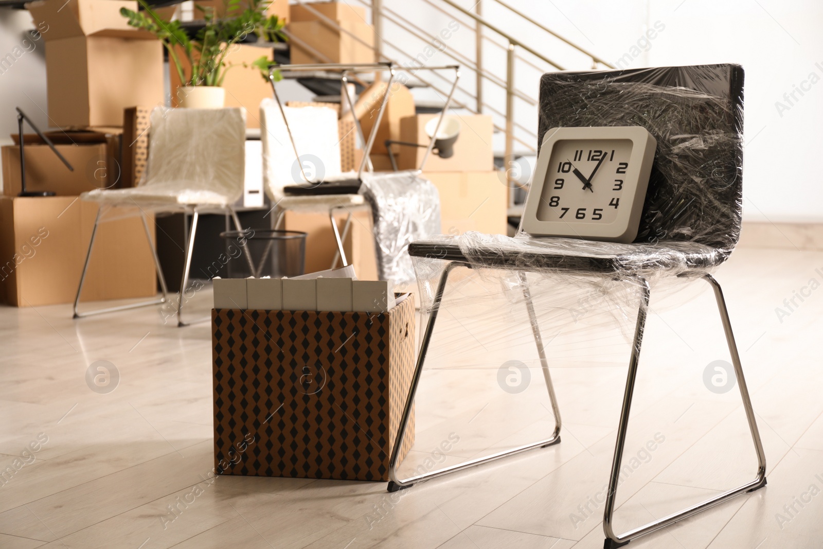 Photo of Packed chair, box and clock in office. Moving day