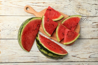 Slices of delicious ripe watermelon on white wooden table, flat lay