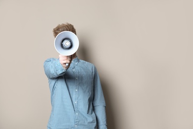 Photo of Young man with megaphone on color background. Space for text
