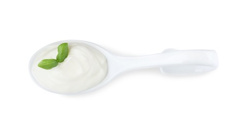 Delicious sour cream with basil in ceramic spoon on white background, top view