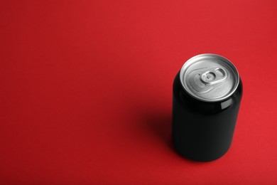 Black can of energy drink on red background. Space for text