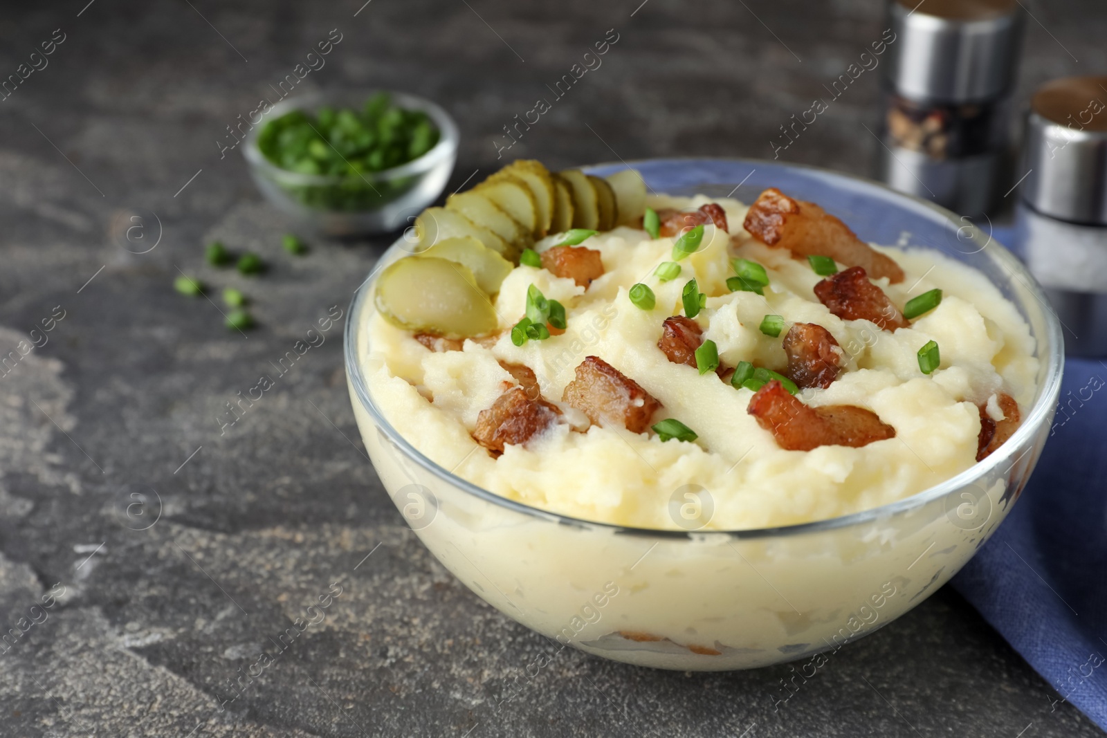 Photo of Potato puree and tasty fried cracklings on grey table. Cooked pork lard