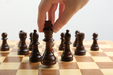 Woman putting chess piece on board, closeup. Career promotion concept