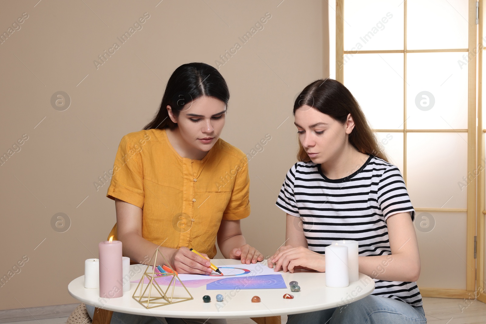 Photo of Astrologer showing zodiac wheel to client at table indoors