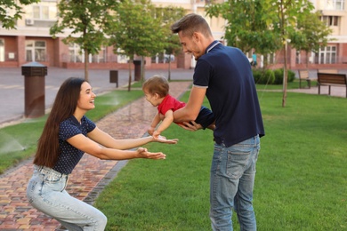 Photo of Happy family playing with adorable little baby in park