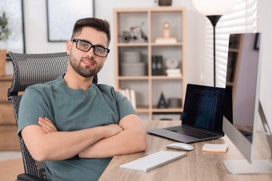 Photo of Happy young programmer working at desk in office