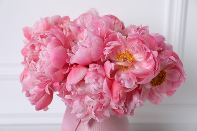 Photo of Beautiful bouquet of pink peonies in vase near white wall, closeup