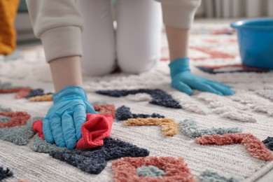 Photo of Woman in rubber gloves cleaning carpet with rag indoors, closeup. Space for text