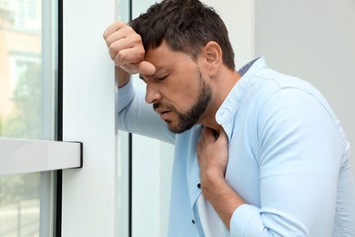 Photo of Man suffering from pain during breathing near window